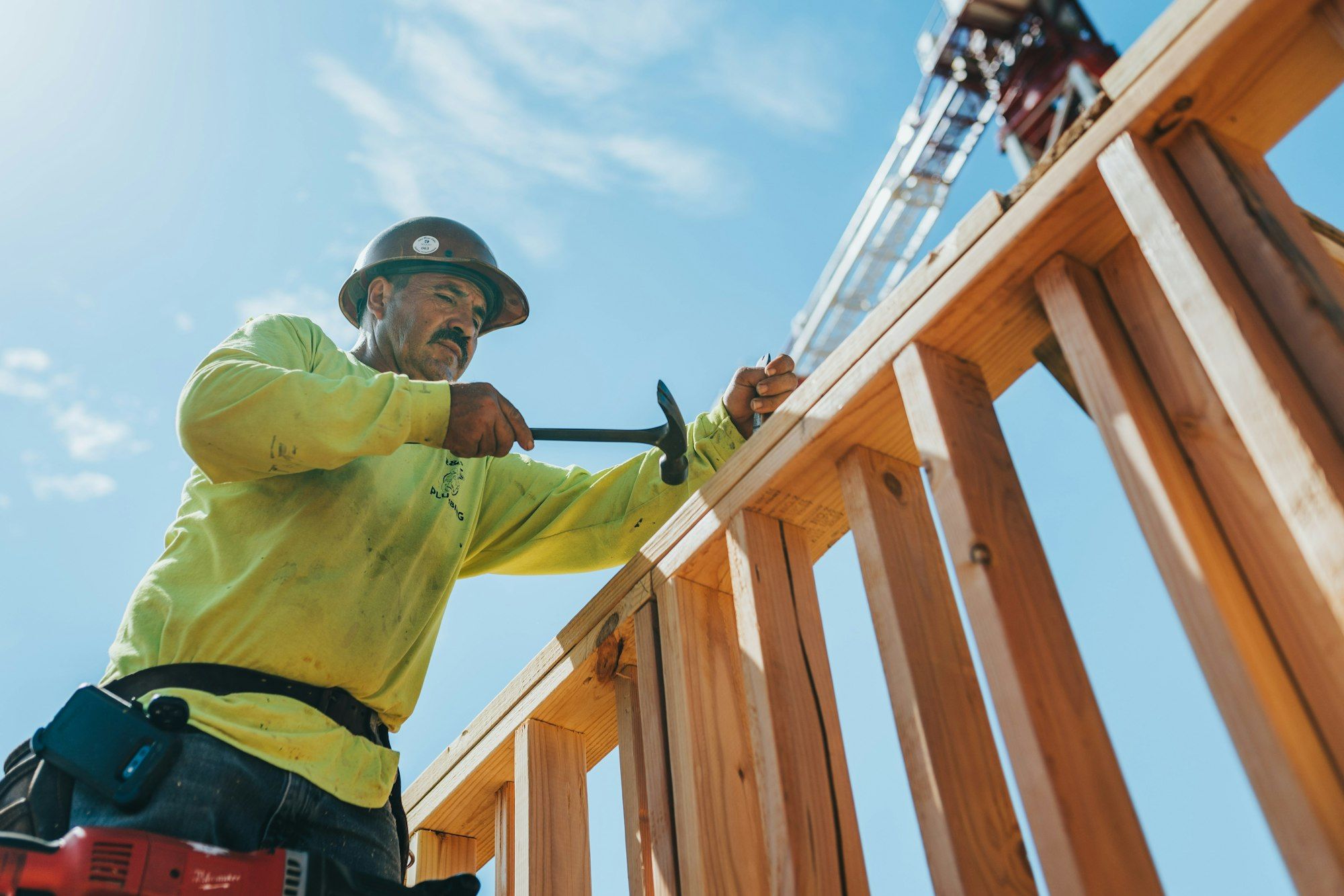 Builder in a hard hat and safety gear working on timber framing