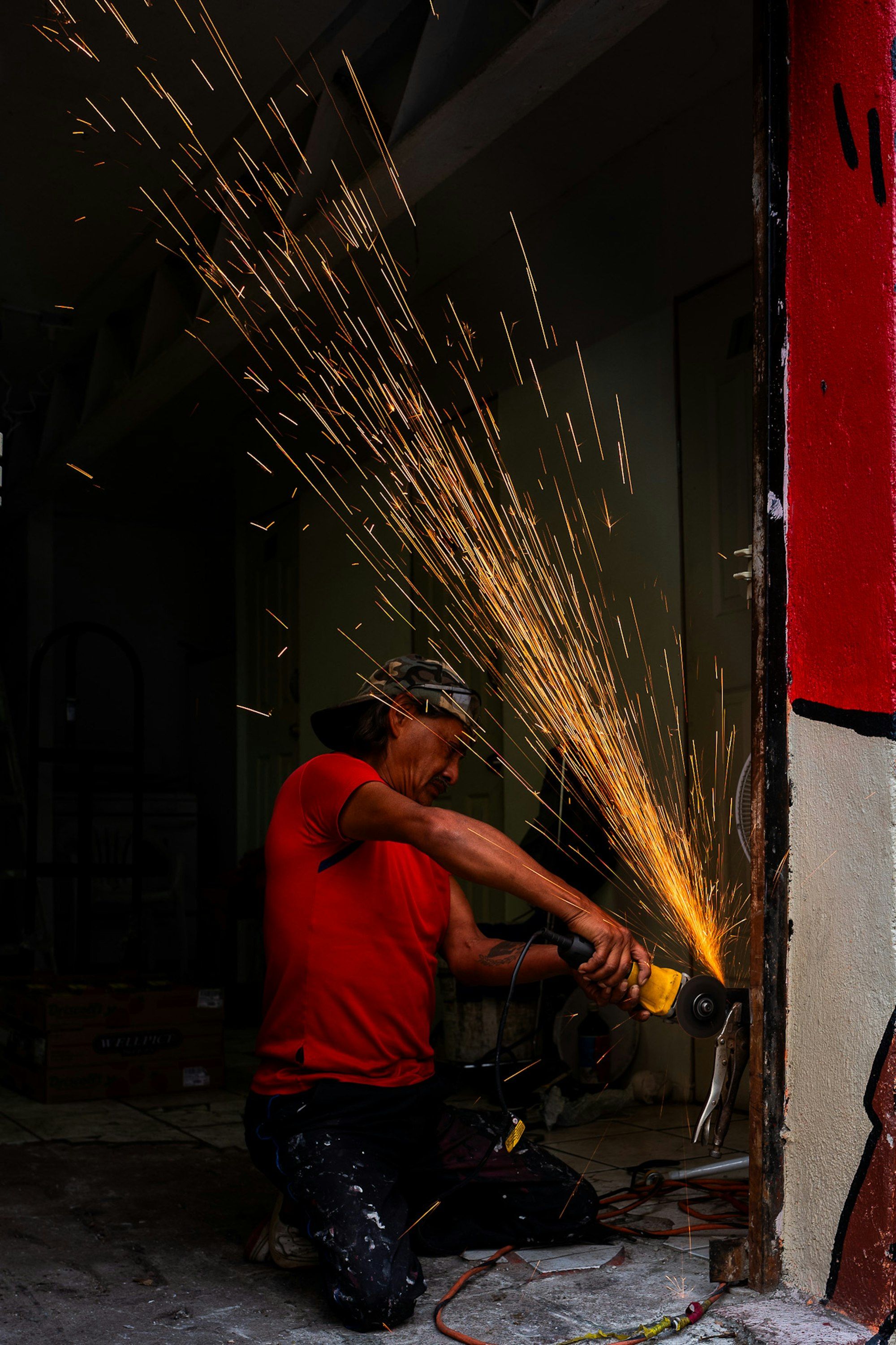 Fabricator cutting steel with an angle grinder, sparks flying