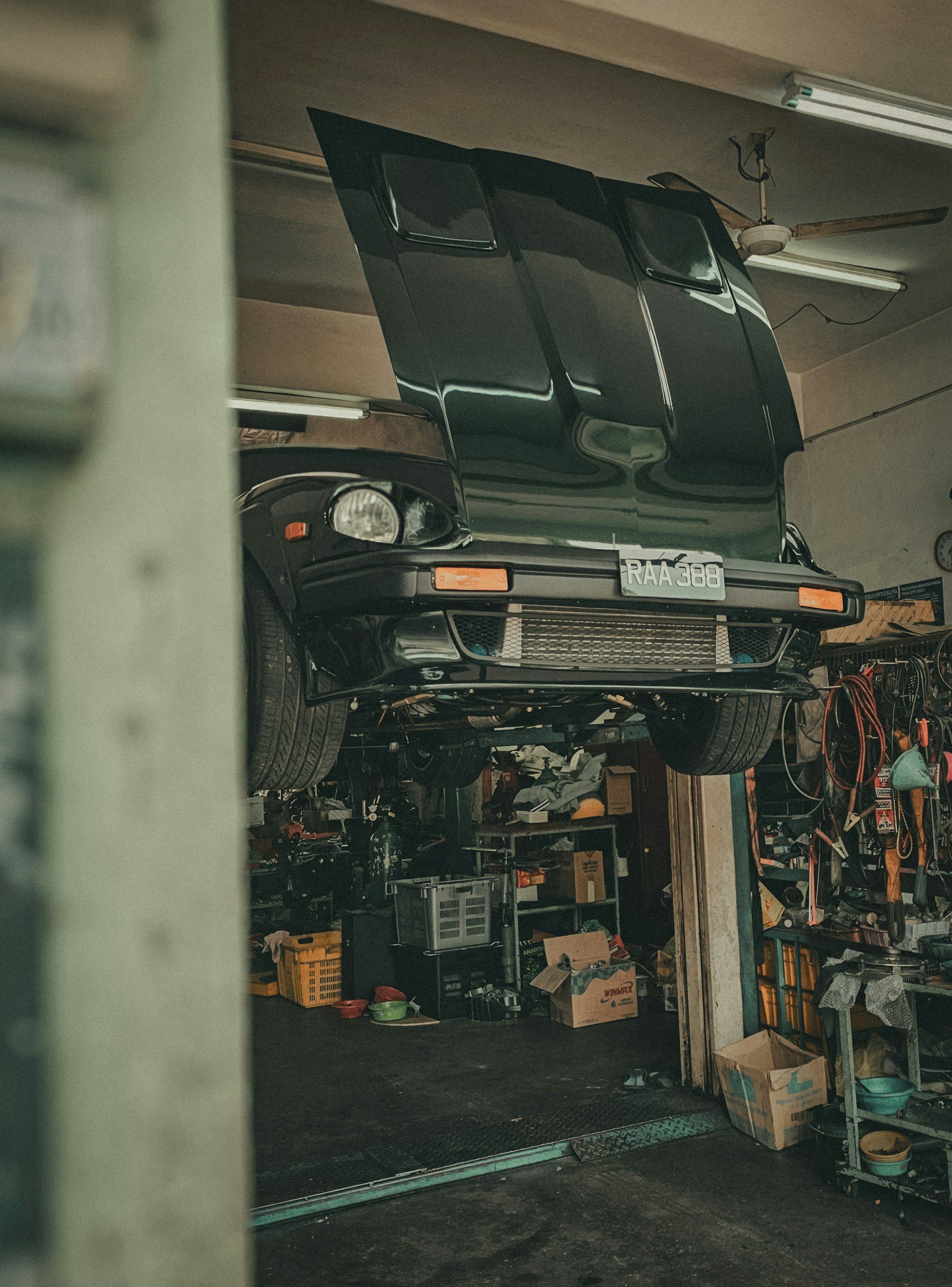 Car raised on a hoist inside a busy automotive workshop
